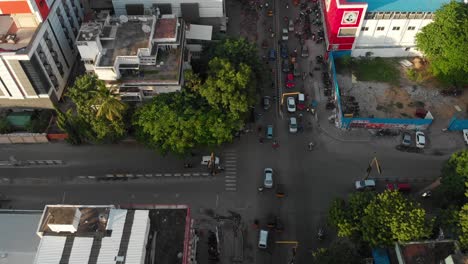 Hovering-over-an-intersection-in-T-Nagar,-Chennai-India,-with-cars-and-motorcycles-driving-beneath