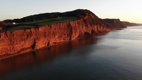 aerial of sidmouth coastline peak hill bathed in golden sunrise light in the morning