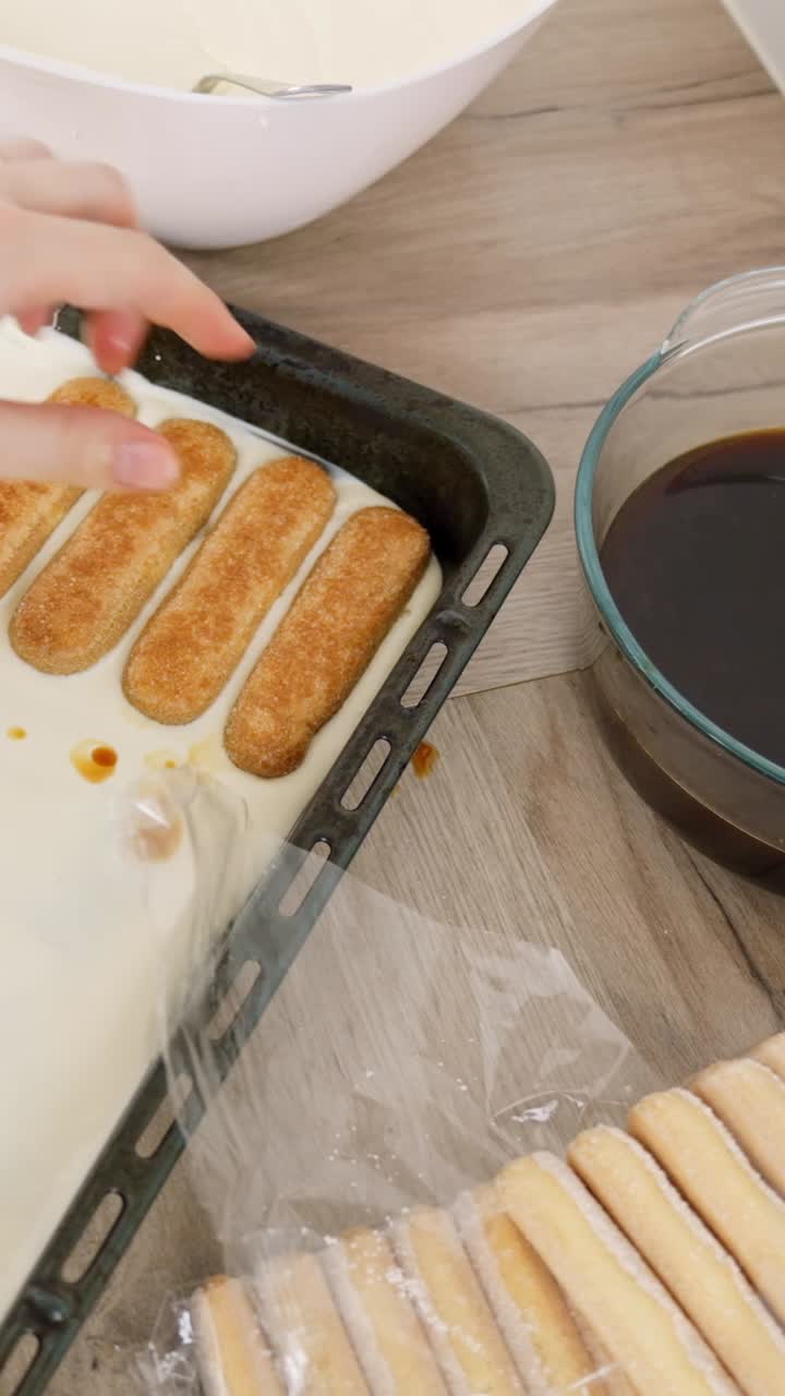 Camadas de biscoitos champanhe embebidos em uma travessa para a montagem do tiramisu, retirando o excesso de café