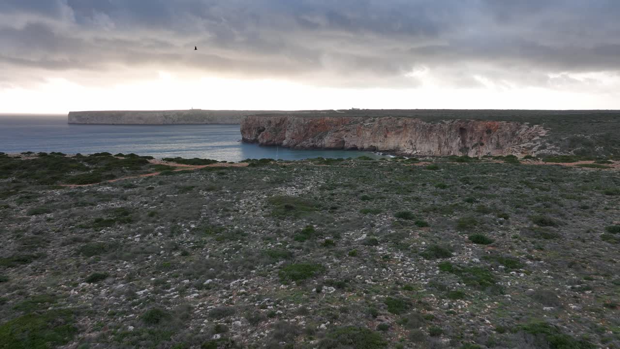 espectacular toma aérea larga de surfistas y un catamarán anclado rodeado de acantilados durante una espectacular puesta de sol