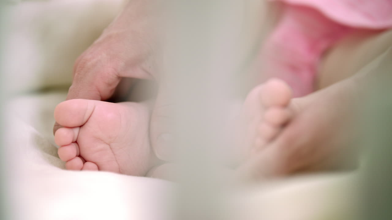 Mother hand touching infant baby foot. Family tenderness. Maternity care