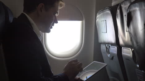 joven hombre de negocios trabajando con pad en el avión