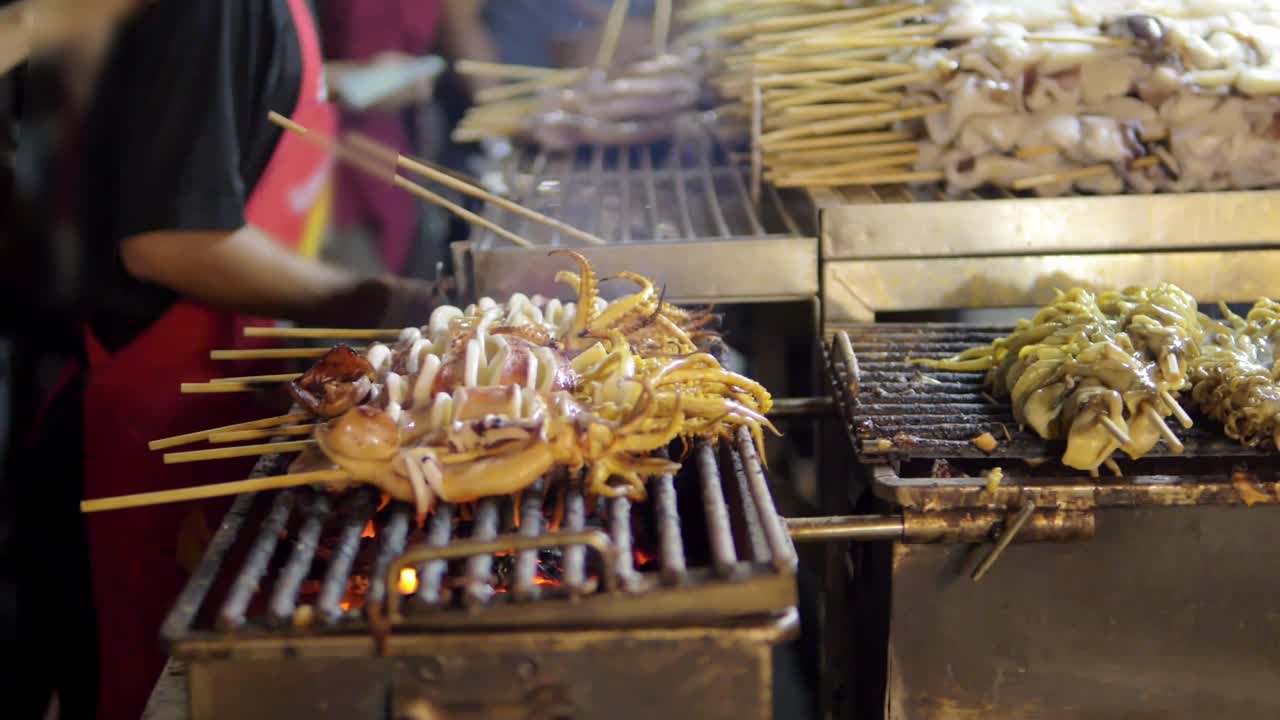 Grilled Squid on a charcoal stove at Yaowarat Road Chinatown, a popular travel destination in Bangkok, Thailand. Slow motion