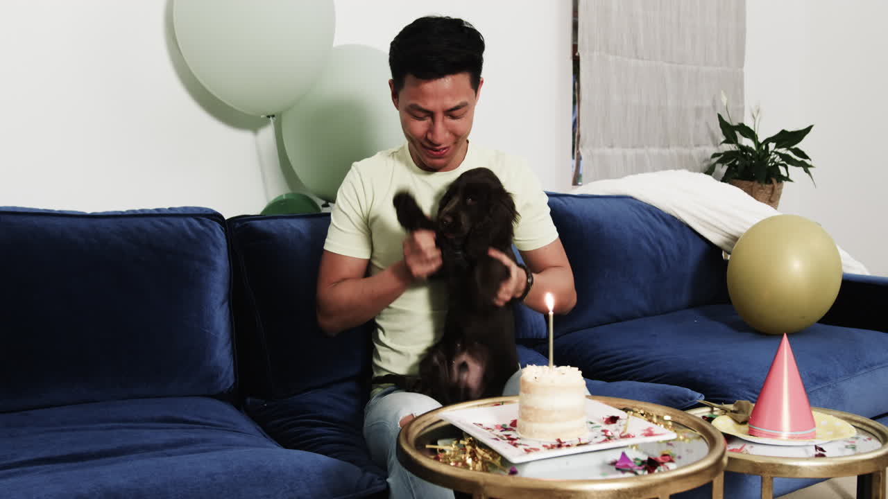 Celebrating birthday, Asian man with dog enjoying cake at home party