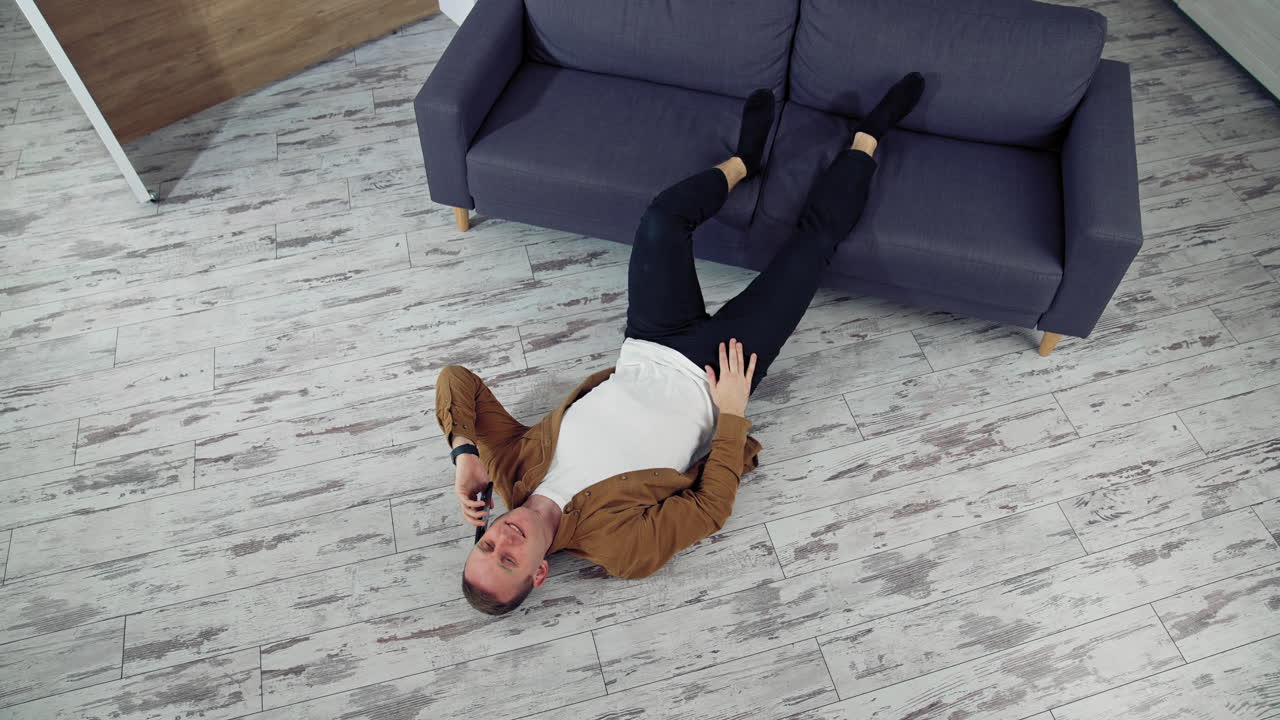 Man relaxing at home on floor. Young man relaxing on the floor and talking on mobile phone