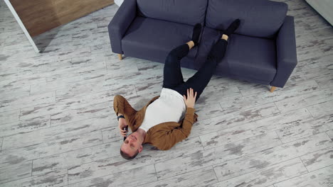 man relaxing at home on floor. young man relaxing on the floor and talking on mobile phone