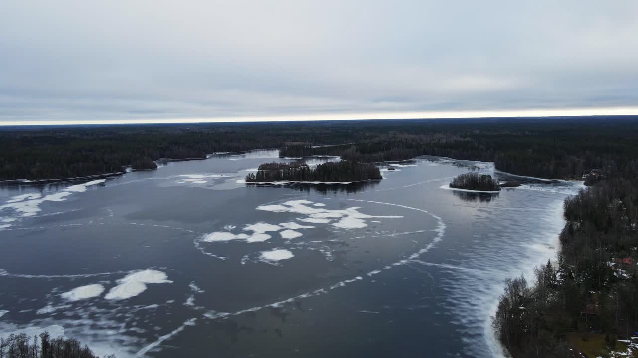 Beautiful aerial of a vast frozen lake with small islands in a large forest in Sweden on a cloudy day