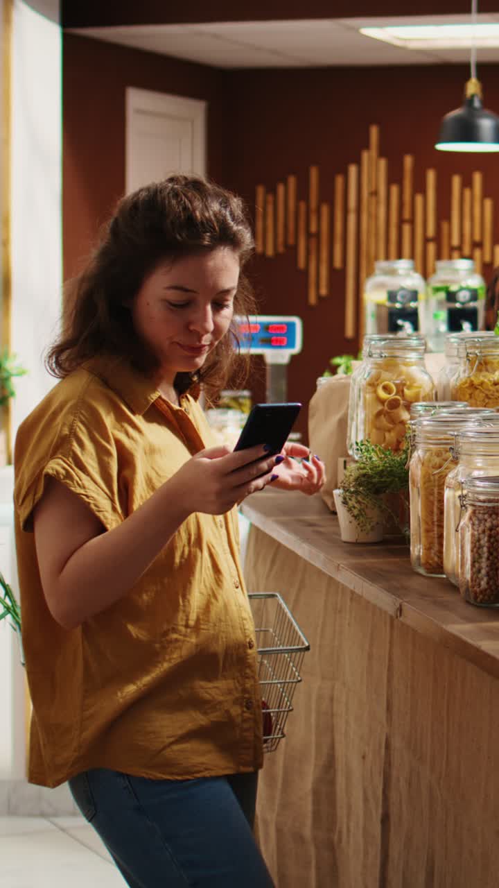 Vertical video Woman uses phone in zero waste shop