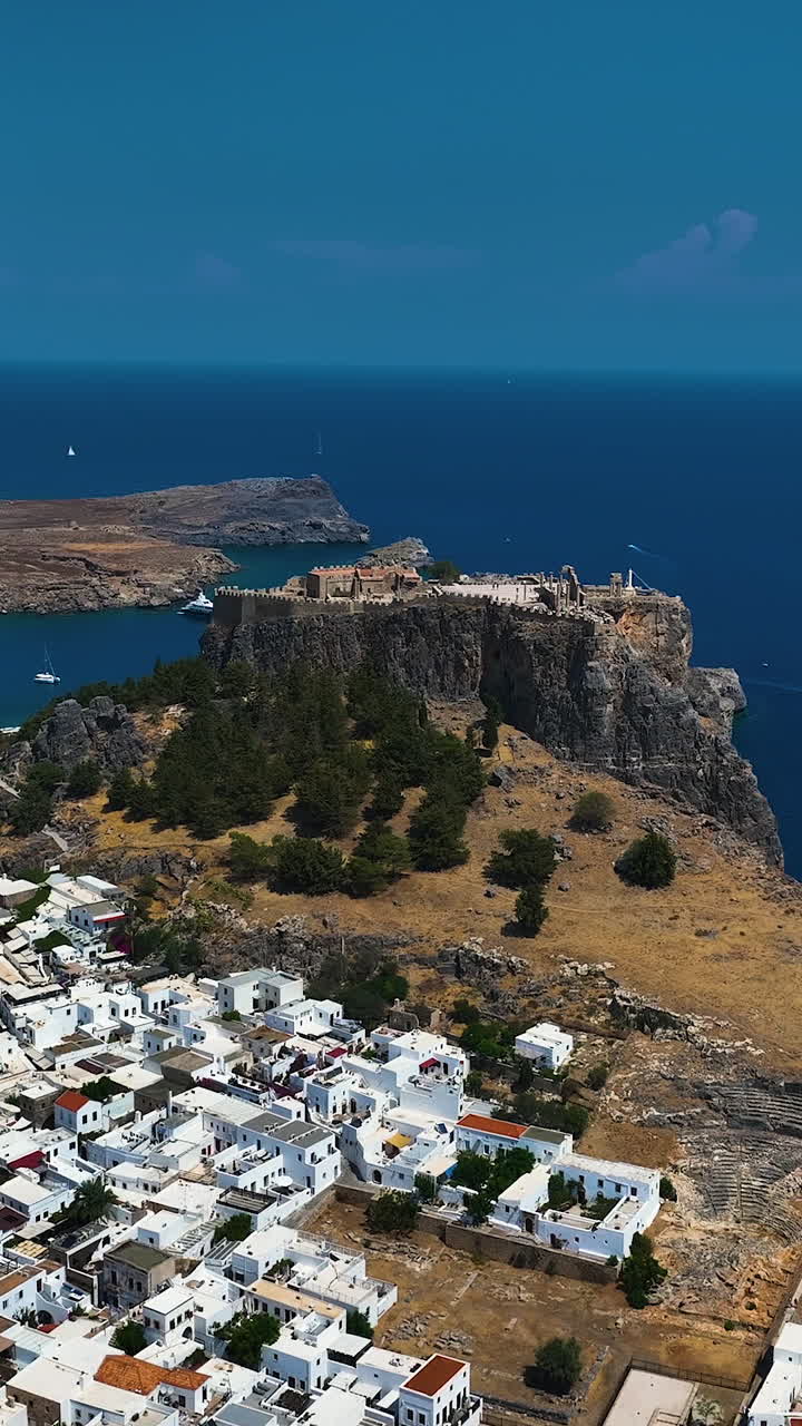 imagen vertical de un avión no tripulado acercándose a la acrópolis de lindos, en el soleado rodas, grecia