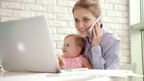 smiling woman with child speaking phone. happy business mother working at home