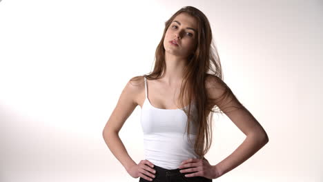 girl with long hair puts hands on hips and smiles to camera