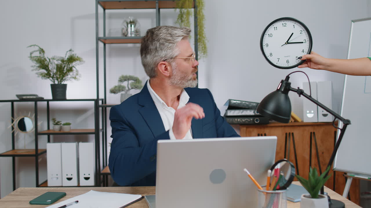 бизнесмен, работающий на ноутбуке в офисе с беспокойством, проверяющий время на часах, опаздывая, крайний срок