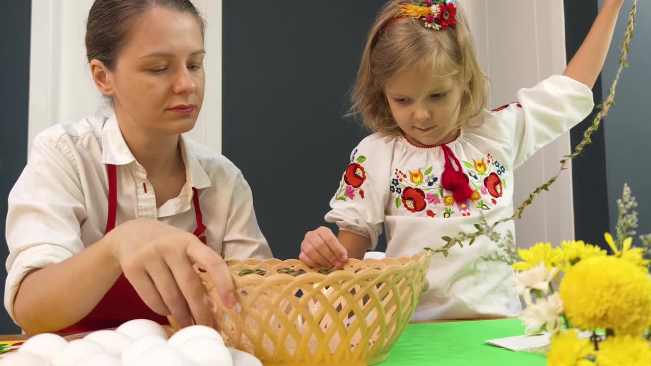 мать и дочь украшают пасхальные яйца