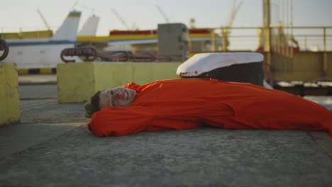 Porträt-Eines-Jungen-Arbeiters-In-Orangefarbener-Uniform,-Der-Sich-Während-Seiner-Pause-Am-Meer-Ausruht