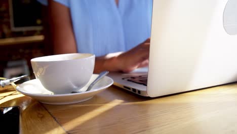 una mujer de negocios usando una computadora portátil en una cafetería.