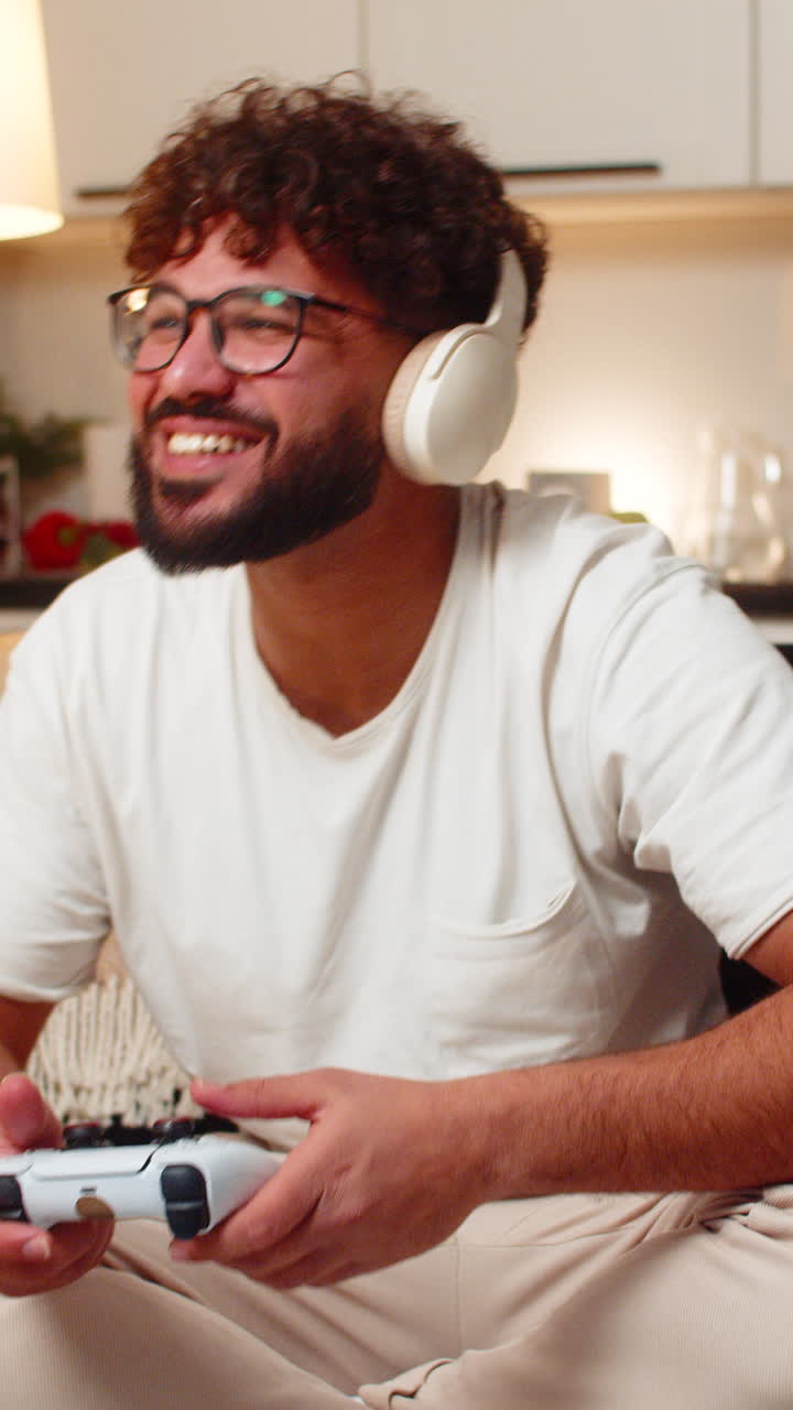 Homem árabe jogando videogame no console, segurando controle, aproveitando a emoção da ação em diversão noturna em casa