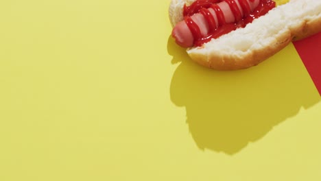 video of hot dog with mustard and ketchup on a yellow and red surface