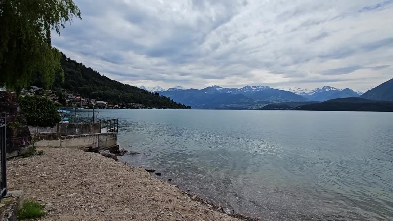 fotografía estática de las montañas suizas desde la orilla del lago thun con cielo nublado