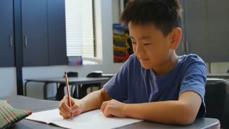 Vorderansicht-Eines-Aufmerksamen-Asiatischen-Schülers,-Der-Am-Schreibtisch-Im-Klassenzimmer-Der-Schule-Lernt,-4k