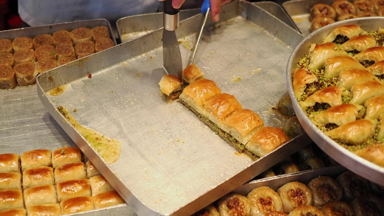 Pasticciere che serve baklava fresco in una pasticceria