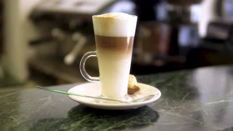 café con leche terminado y listo para ser servido con espuma en la parte superior y dulce a un lado en el ambiente del restaurante a cámara lenta
