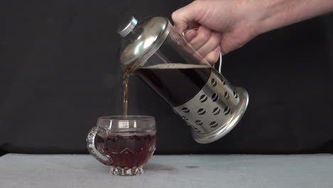 pouring coffee out of a french press into a glass mug.