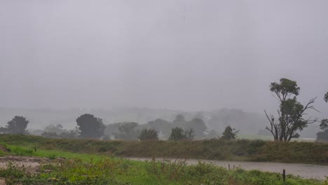 Ein-Zeitraffer-Von-Dunklen-Sturmregenwolken,-Die-über-Die-Ländliche-Landschaft-Australiens-Hereinrollen,-Während-Regen-Und-Sonne-Durch-Die-Wolken-Brechen