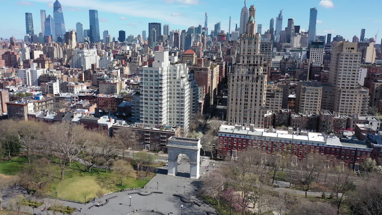 A high angle view over Washington Square Park in NYC. The drone camera dollys in - descends towards the Washington Square Arch below. The park is empty - the city is quiet on this sunny morning.