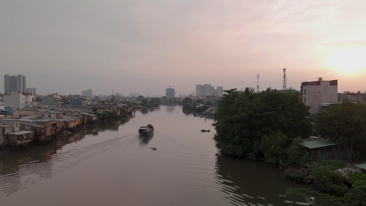 barco fluvial vietnamita en el canal con chozas urbanas en el barrio pobre de la ciudad de ho chi minh mostrando casas y horizonte en la hermosa luz dorada de la noche