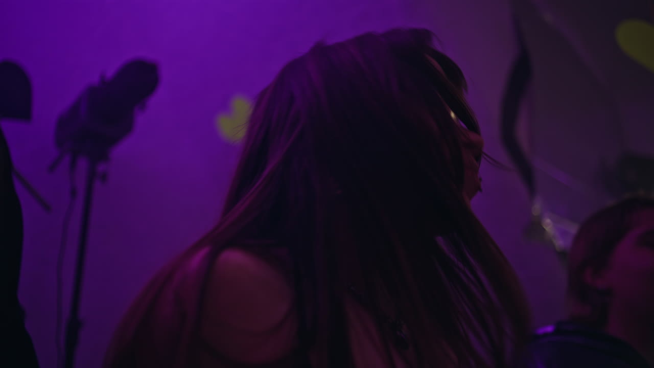 Primo piano di clubber sorridenti che ballano sotto le luci al neon del club. Donna gioiosa che si diverte al bar.