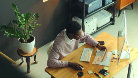 black man working on pc and reviwing documents in the office