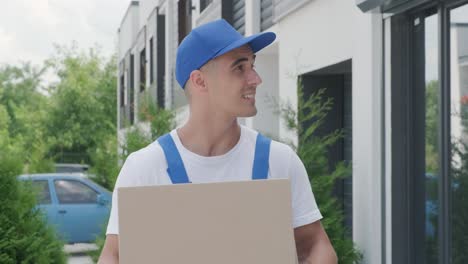 young courier holding a parcel walking on the street to deliver a box directly to a customer home. concept of courier, home delivery, e-commerce shipping