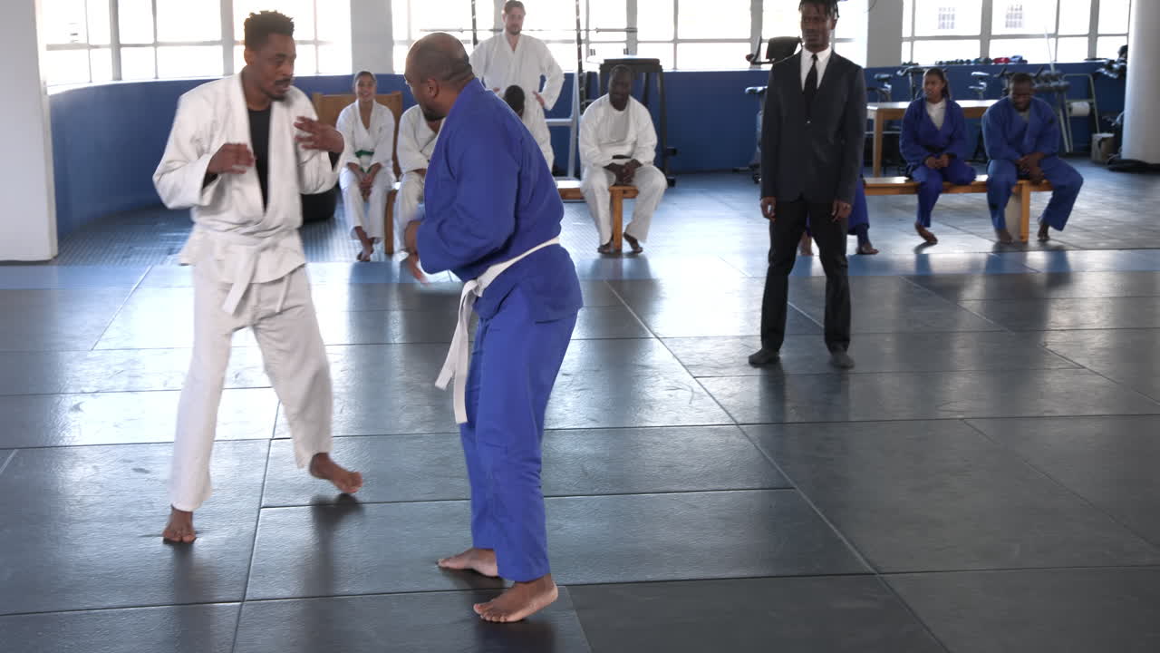Practicing judo, athletes in blue and white uniforms sparring on mat