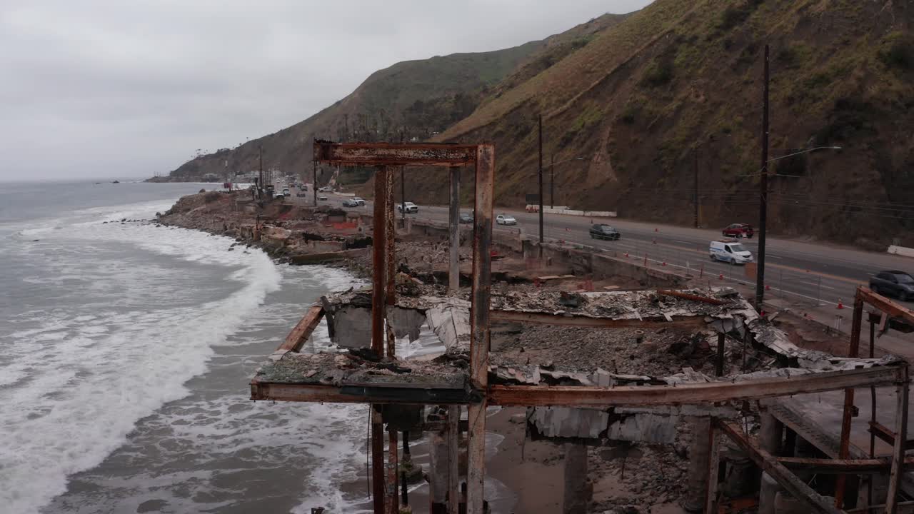 Close-up panning aerial shot of the remains of a burned home along Pacific Coast Highway after the Palisades Fire in Los Angeles, California. 4K