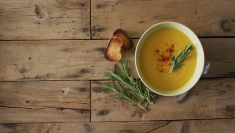 video of cream vegetable soup in bowl on wooden table with rosemary