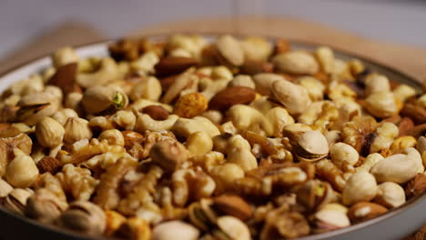 fotografía de cerca de las nueces que caen en un cuenco que contiene caju, cacahuetes tostados secos, pistachos, nueces y avellanas