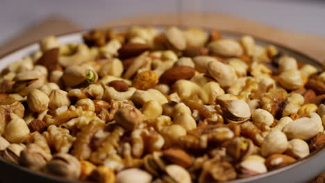 close up shot of nuts falling into bowl containing cashews dry roasted peanuts pistachio walnuts and hazelnuts