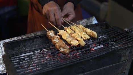 Ein-Verkäufer-In-Bangkok-Grillt-Traditionelle-Thailändische-Spieße-Für-Streetfood