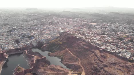 lagos ranisar padamsar cerca del fuerte de mehrangarh y bordeando la ciudad azul de jodhpur, rajasthan, india - tiro panorámico lento aéreo