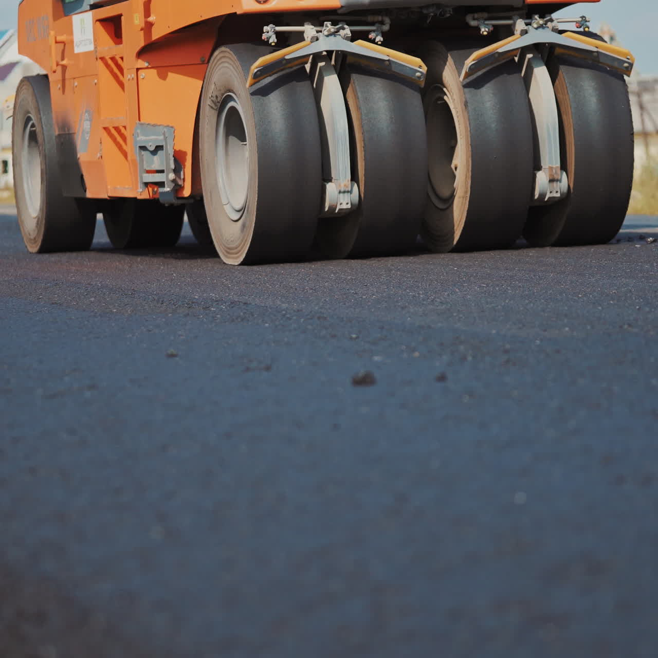 Modern asphalt roller machine stuck and press hot asphalt while making a new road. Big black wheels of a roller machine working on the new road.