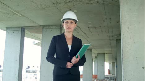gerente de construcción femenina con un plano en el sitio de construcción presentando el proyecto mirando a la cámara