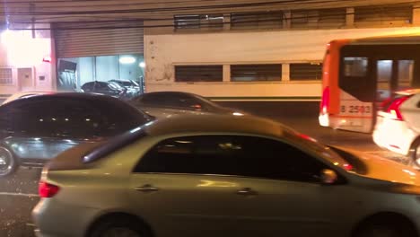 coches que pasan por la noche lluviosa en la calle de la ciudad, gotas de agua