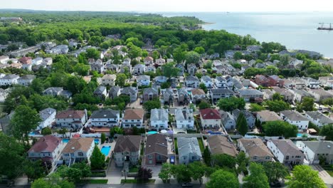 idyllic american residential area with green trees and swimming pools near south shore of staten island, new york - drone panorama wide shot