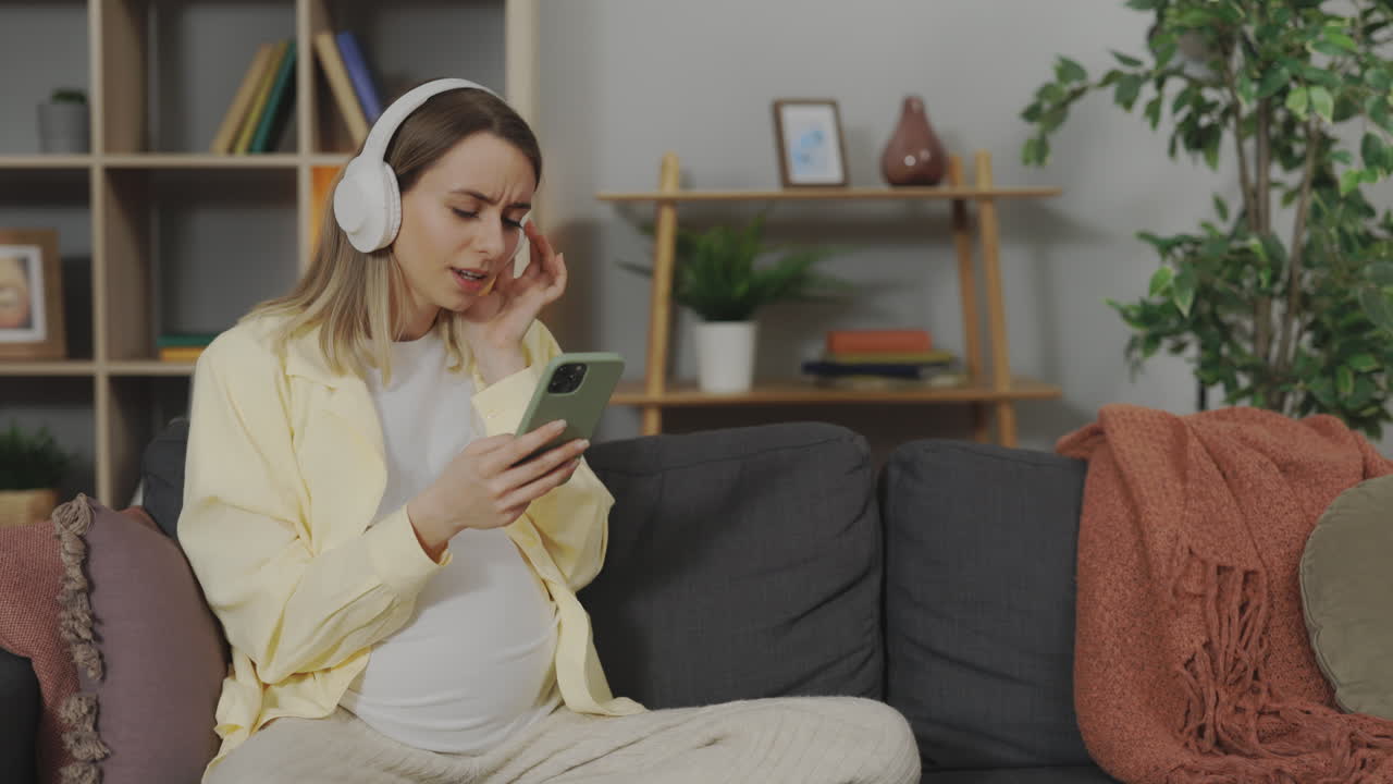 Donna incinta che ascolta musica e usa lo smartphone