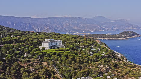 Saint-Jean-Cap-Ferrat-France-Aerial-v6-establishing-pull-out-shot-away-from-luxurious-four-seasons-grand-hotel-du-cap-ferrat,-overlooking-at-the-whole-peninsula---July-2021