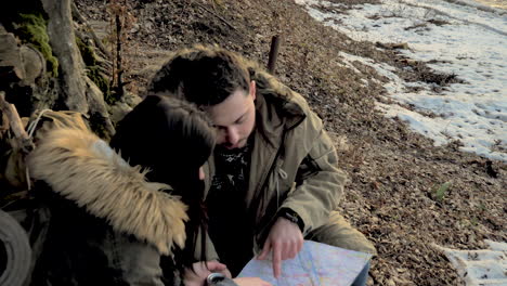 una pareja caucásica revisando el mapa en un bosque.