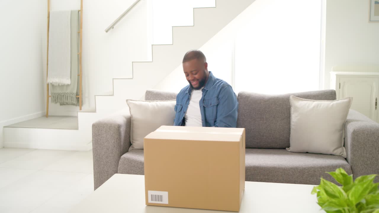 Mid-aged African American man seeing phone alert, opening box and checking contents at home