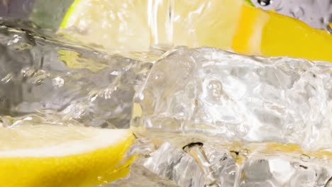 slow motion shot of transparent liquid falling on ice cubes and lemon slices, macro shot