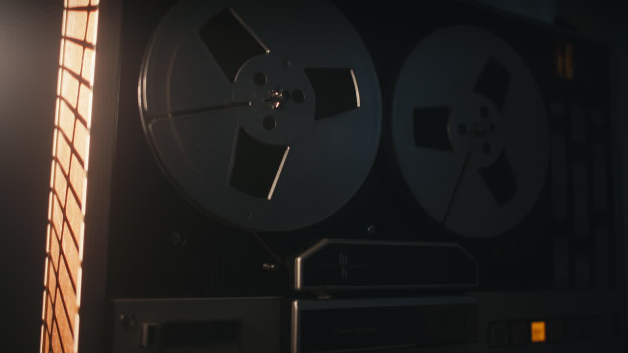 A vintage tape recorder spinning spools in a red blinking light