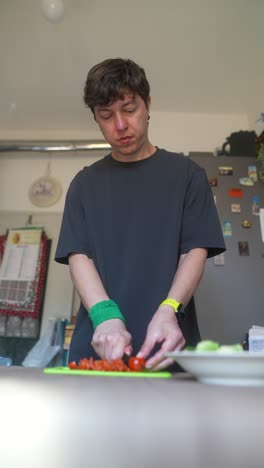 man chopping tomatoes in kitchen